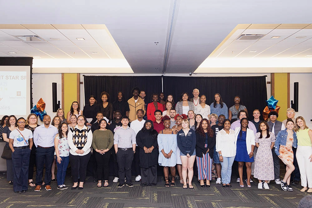 Group of men and women posing for picture inside a conference room